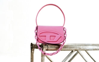Bright pink handbag with a large embossed logo and chunky chain detail on a metallic rail.