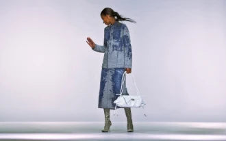 Model wearing a blue denim coordinated outfit with a white handbag and green boots.