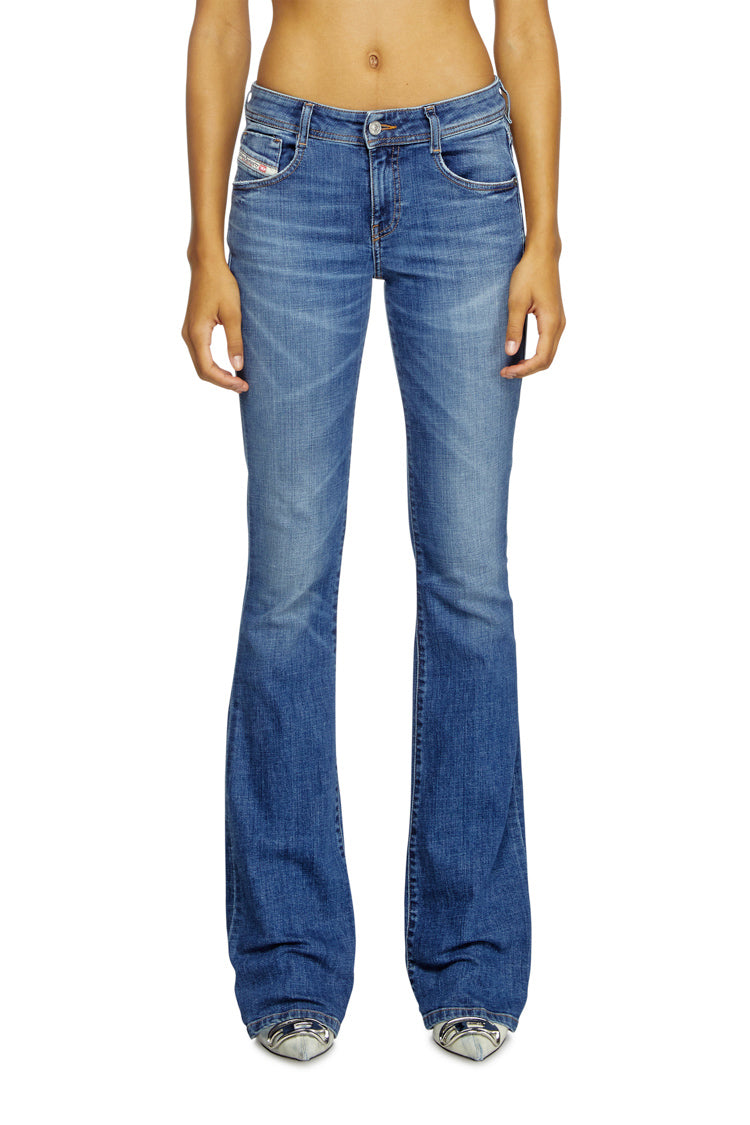 Blue flared jeans worn by a person on a white background