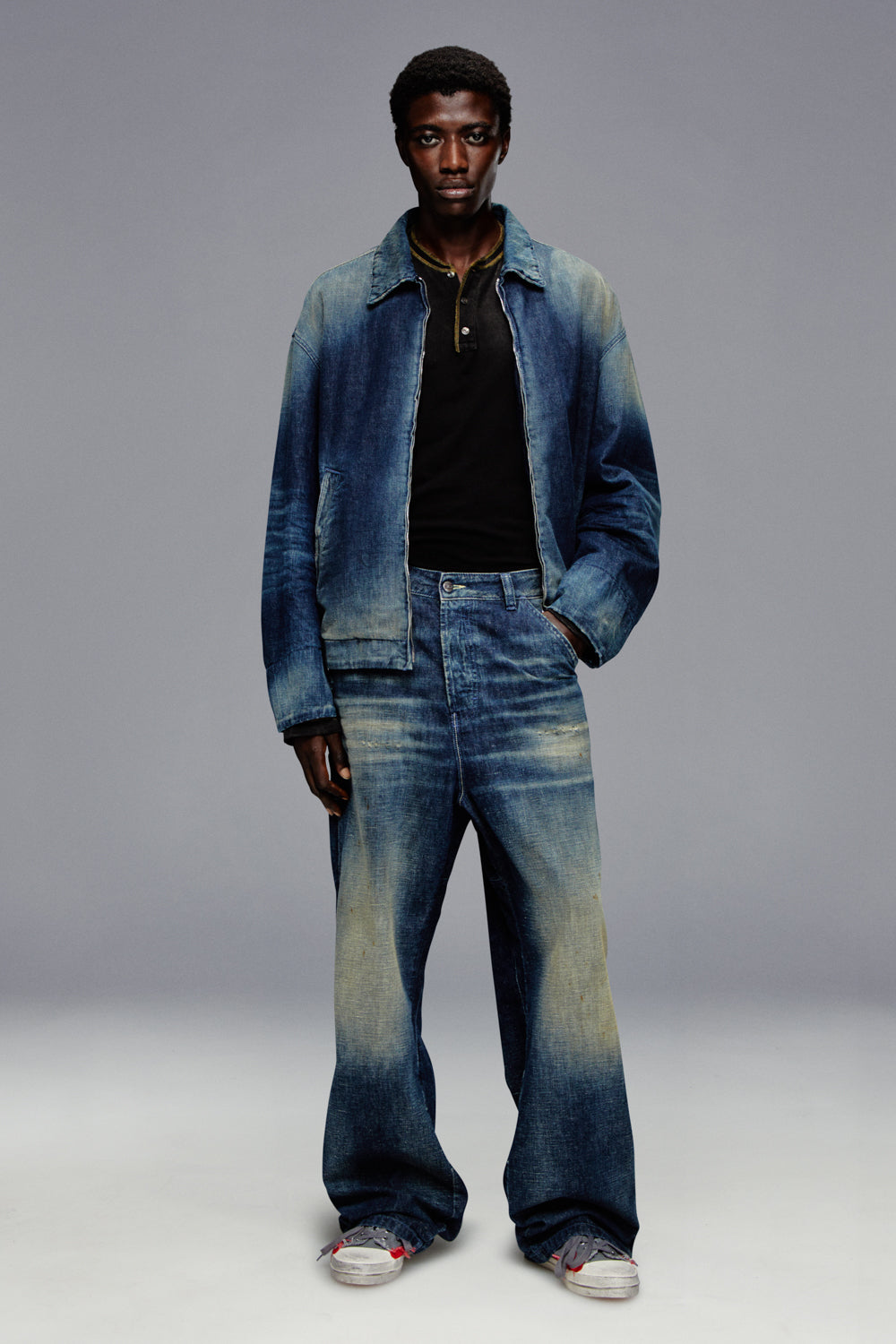 Man wearing a blue denim jacket and jeans on a gray background