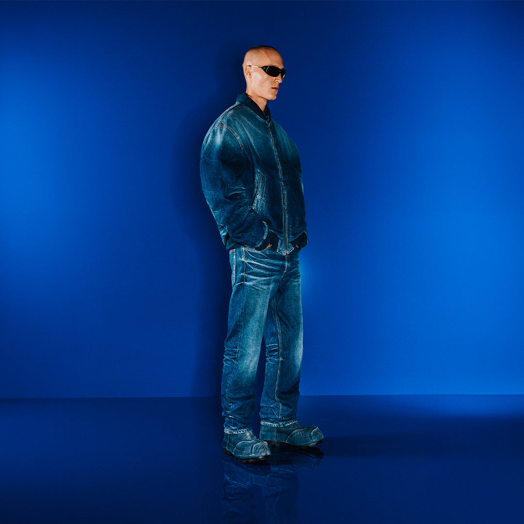 Man wearing a blue jacket and sunglasses against a blue background